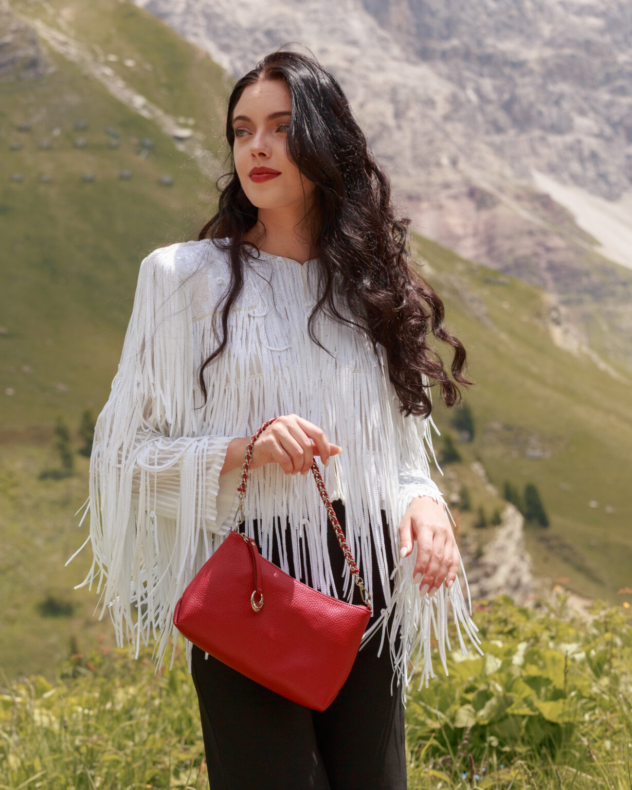 Una modella indossa una pochette in pelle di Pelletteria Veneta, di colore rosso con manico rimovibile e decorazione in metallo